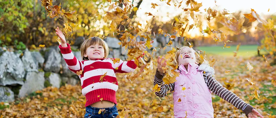Barn som kastar upp en massa löv i luften