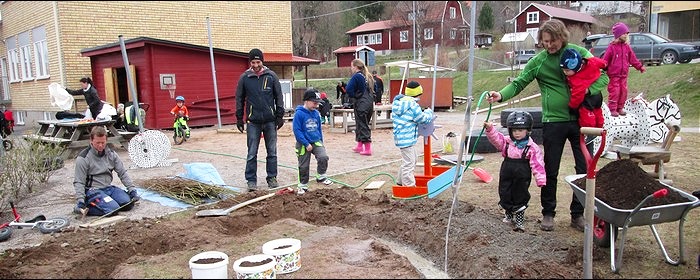 Barn och föräldrar som hjälps åt att gräva och fixa ute på gården.