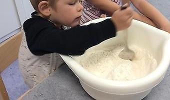 Barn som rör om mjöl i bunke.