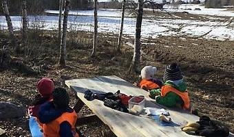 Barn som sitter runt ett bord utomhus
