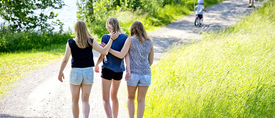 Tre kvinnor som går på en grusväg en sommardag