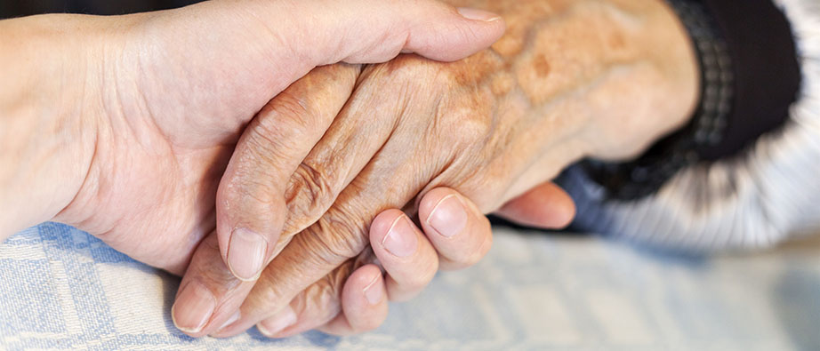 Två äldre personer som håller varandras händer
