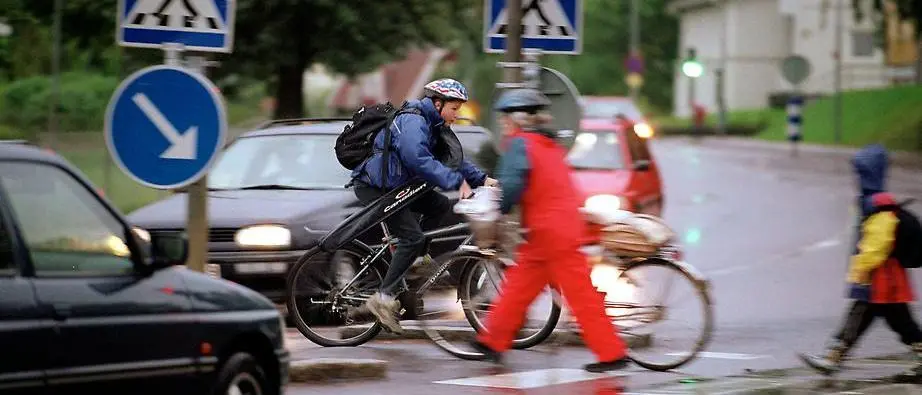 Övergångsställe med cyklister gående och bilar. Foto Ulf Palm
