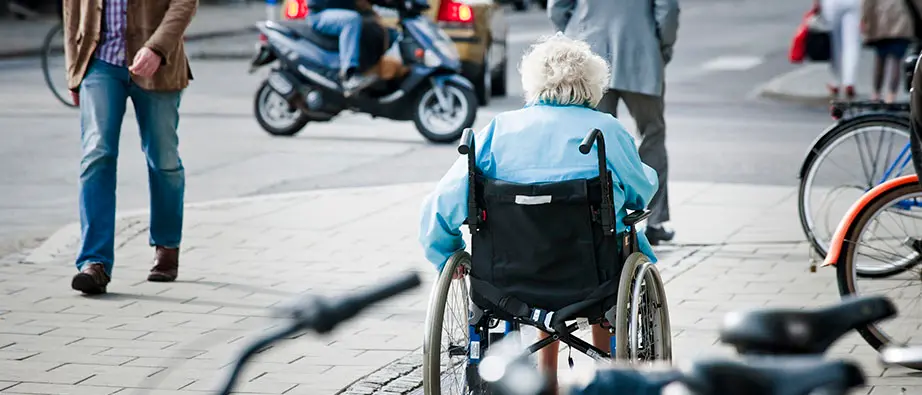 Äldre dam i rullstol i trafiksituation.