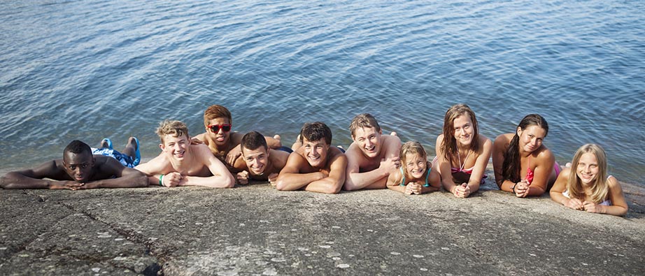 Flera ungdomar som ligger på en klippa med vatten i bakgrunden