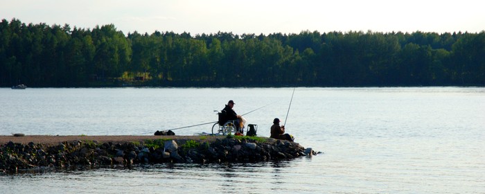En person i rullstol som sitter och fiskar vid en sjö