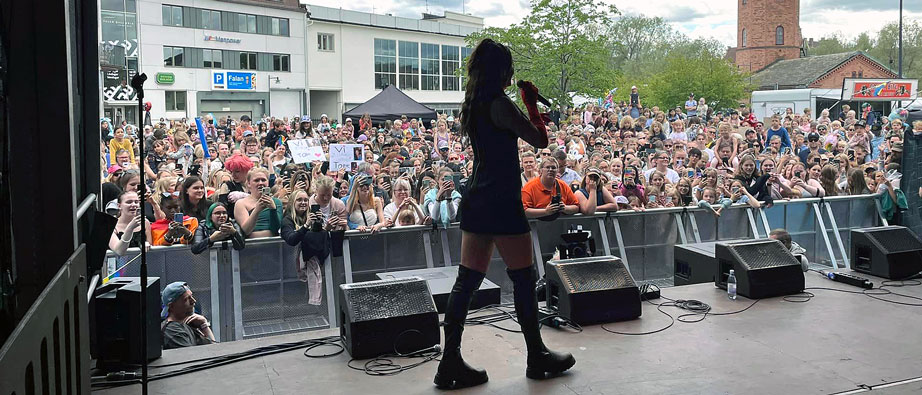 En kvinna står och sjunger på en scen inför en stor publik.