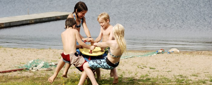 Fyra barn som leker på en gemensam lekutrustning vid en badplats