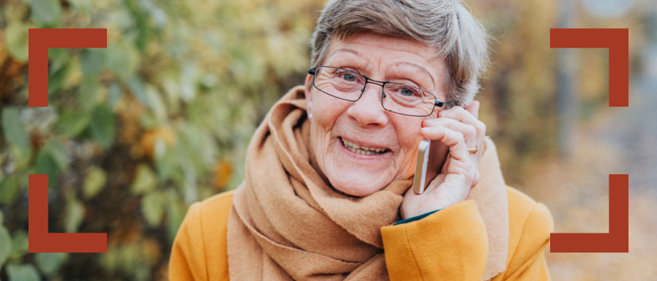 Äldre glad dam pratar i mobil.