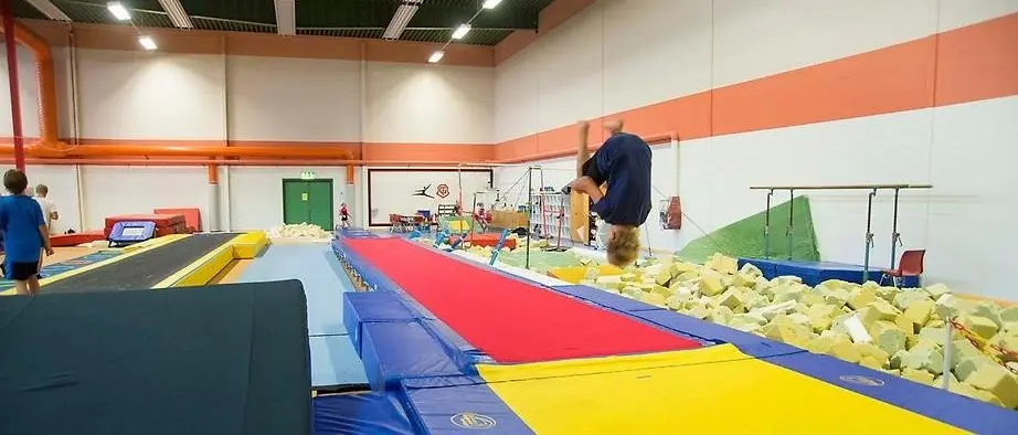 Gymnast gör kullerbytta i Gymnoshallens skumgummigrop.