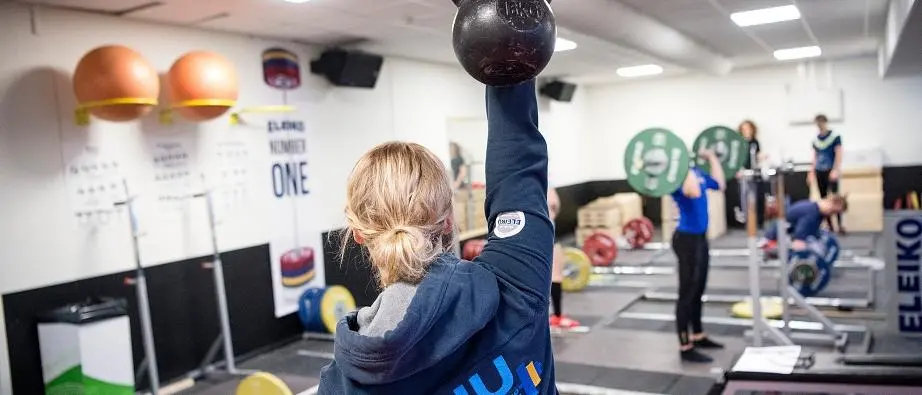 En kvinna lyfter upp en vikt under träning i tyngdlyftningshallen.