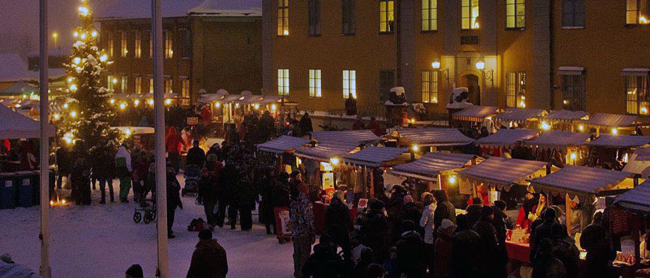 Kvällsbild från julmarknaden med marknadsstånd och besökare.