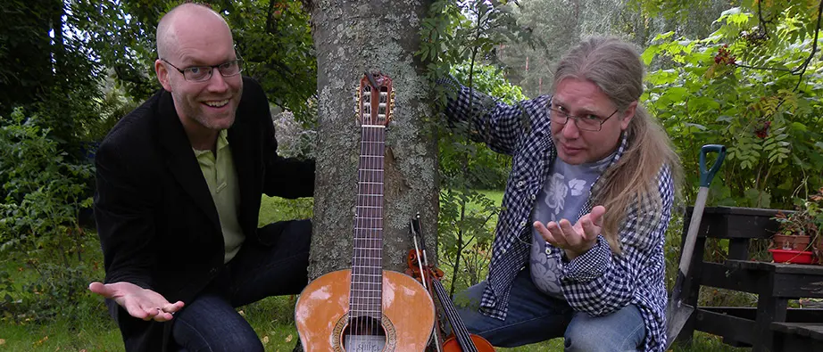 Artisterna Stefan och Pellas med sin gitarr lutandes mot ett träd. 