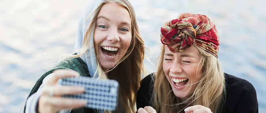 två unga tjejer tar en selfie med mobiltelefon