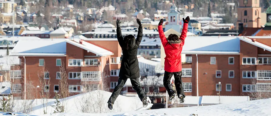 Två personer som hoppar upp i luften utomhus en vinterdag.