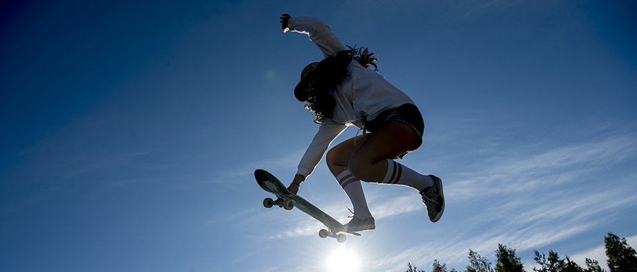 En tjej som hoppar upp i luften med sin skateboard.