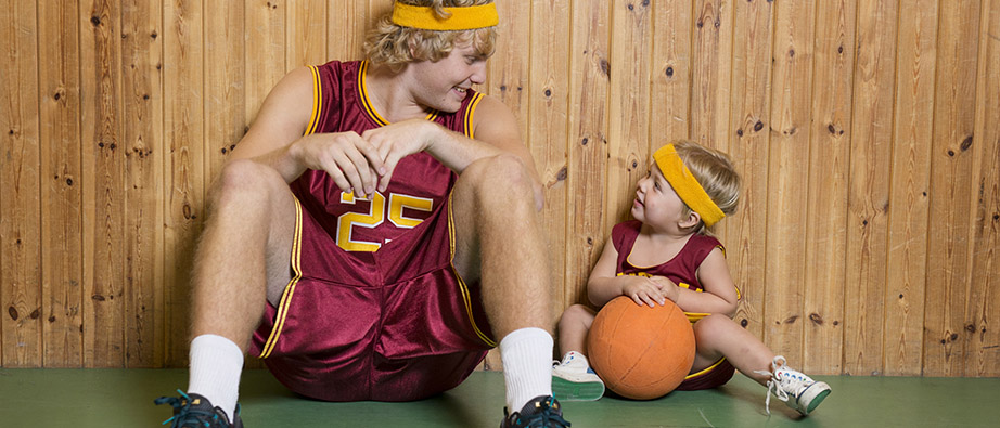 pappa och son sittandes mot vägg med basketboll.