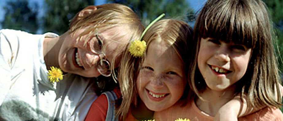 Tre flickor står tätt intill varandra i solskenet