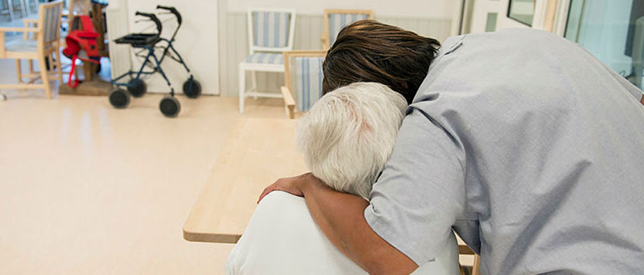 Vårdare kramar om en äldre kvinna.