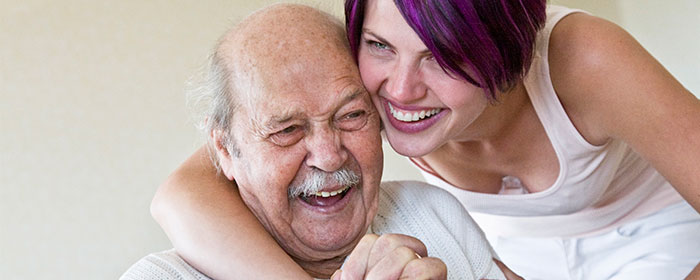 Ung kvinna kramar om en äldre man och båda skrattar