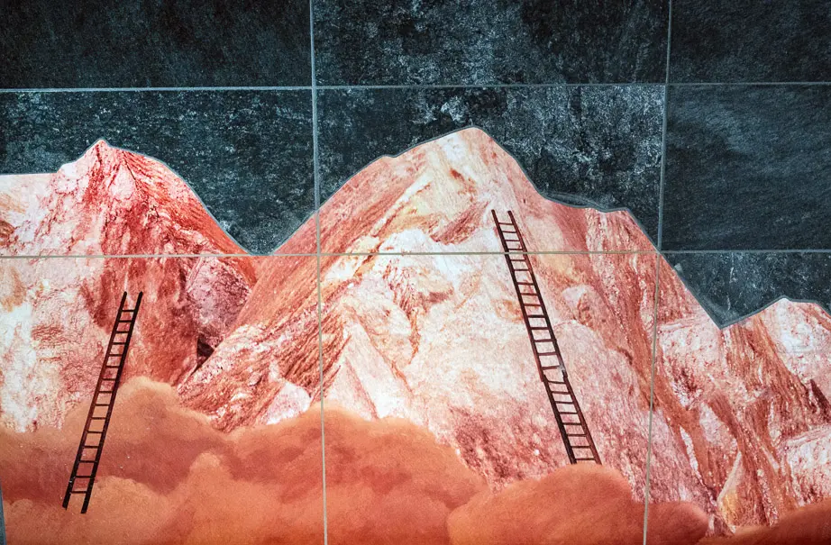 Konstnär: Helena Blomqvist. Närbild på det målade kopparberget. Berget går i olika nyanser av kopparfärg och på berget står två stegar lutade.