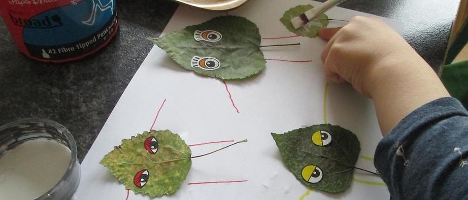 Barn som limmar löv på ett papper