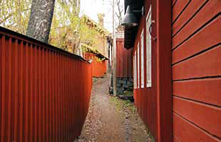 Smal gata med rött hus på ena sidan och rött plank på andra.