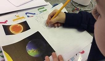 Ett barn som skriver och ritar på ett papper