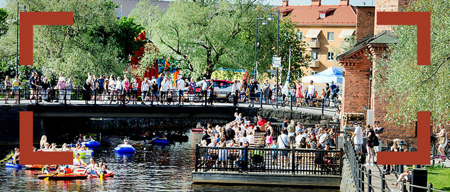 Människor på bro som tittar ner på gummibåtar i ån
