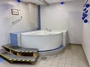 Ett vitt och blått badrum med ett bad i hörnet