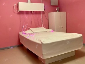 Ett rosa rum med en stor vit säng i mitten