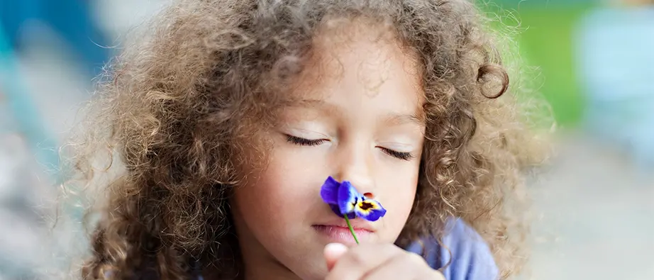 Barn som luktar på en blomma