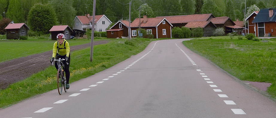 Cyklist cyklar mot kameran på en enfältsväg på landsbygden.