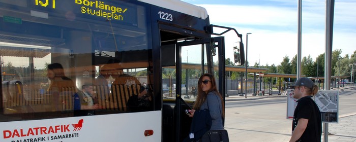 En tjej bärande solglasögon klier på en Borlängebuss följt av en kille i keps