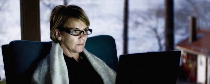 En kvinna sitter framför en data skärm i skymningen