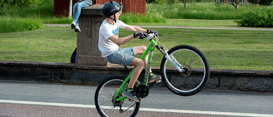 En pojke åker på bakhjulet på sin cykel