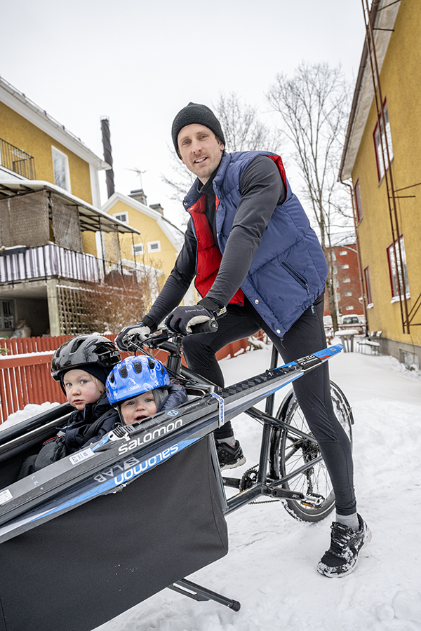 Både Emil och hans barn tittar glatt in i kameran och ser redo ut att ta sig an de snöklädda gatorna med cykeln.