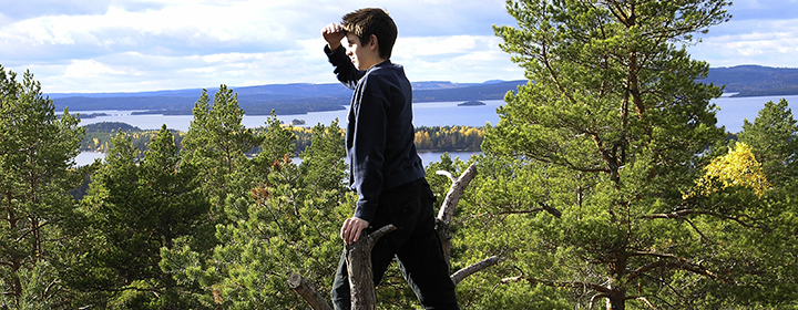 Ung pojke som ser över skog.