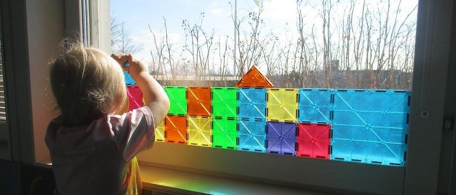 Ett barn som bygger med plattor på ett fönstret