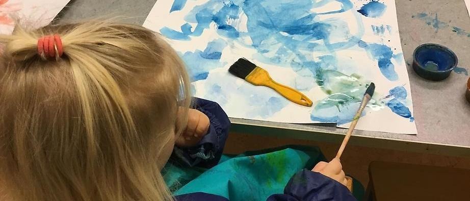Ett barn som sitter och målar med vattenfärg