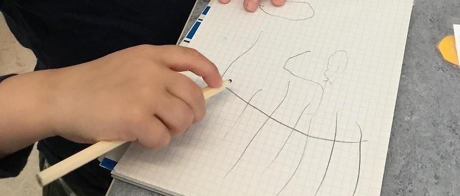 Ett barn som sitter och ritar på ett papper