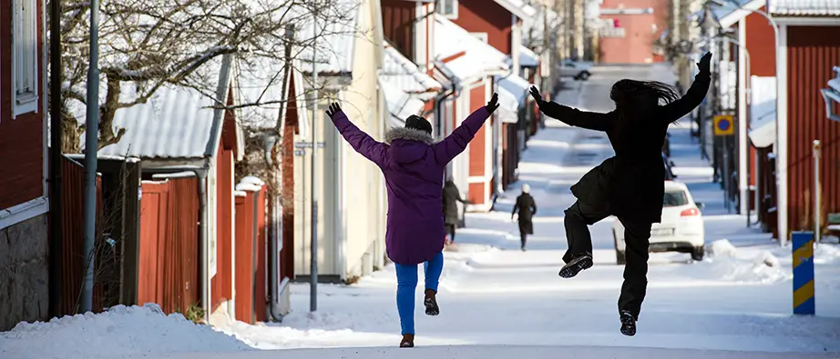 Två personer som hoppar upp i luften på en väg en vinterdag.