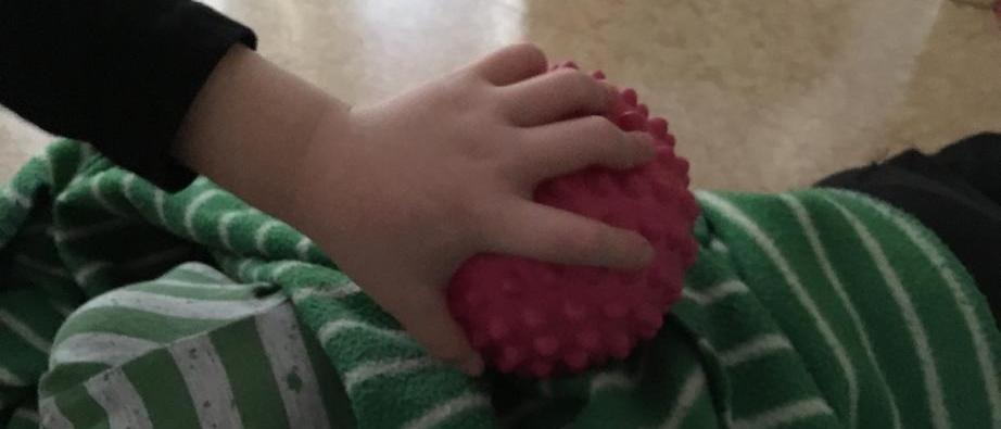 En barnhand som håller i en gummiboll