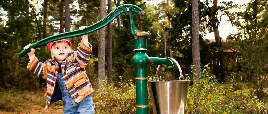 Barn som pumpar upp vatten ur en brunn