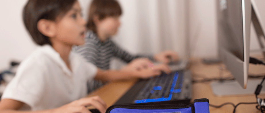 Två barn som sitter och spelar på datorn