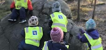 Barn klättrar på en stor sten