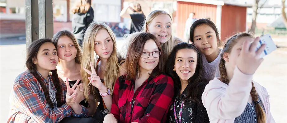 Flera unga tjejer som står tillsammans och tar en selfie