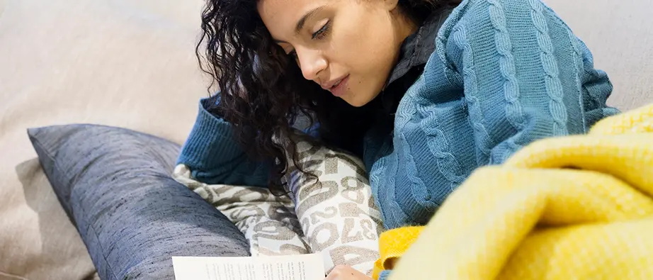 En flicka som ligger på en säng och läser en bok