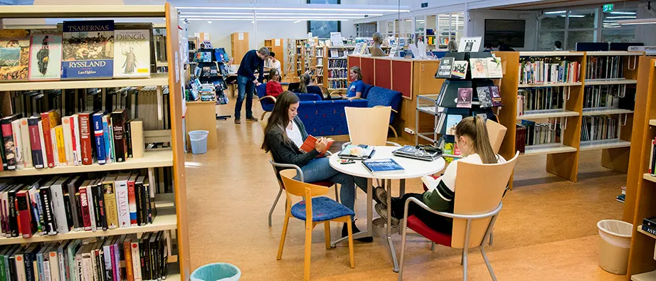 Lugnetgymnasiets bibliotek och flera ungdomar som sitter och läser där
