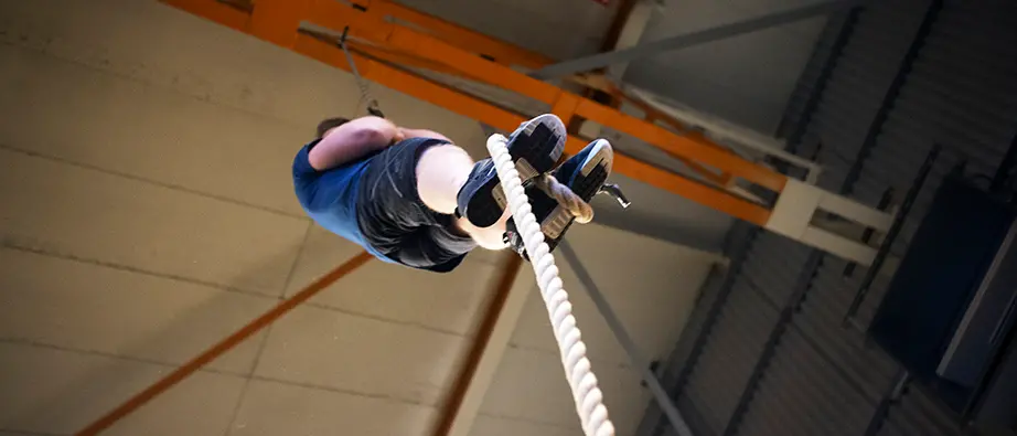 Kille som tränar och klättrar uppför ett rep